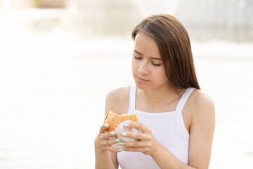 fast food, a teenage girl in the park has a burger