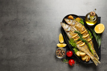 Tasty homemade roasted pike perches served on grey table, flat lay and space for text. River fish