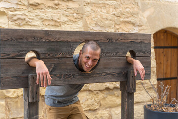 Portrait of man in a wooden pillory - obrazy, fototapety, plakaty