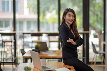 Pleased asian business woman with crossed arms looking at the camera.