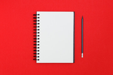 Blank spiral notebook and pencil on red background. Top view with copy space for input the text.