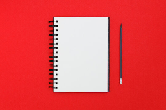 Blank spiral notebook and pencil on red background. Top view with copy space for input the text. - Powered by Adobe