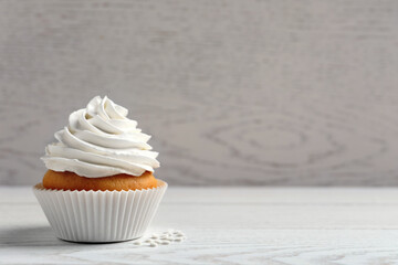 Delicious cupcake with cream on white wooden table. Space for text