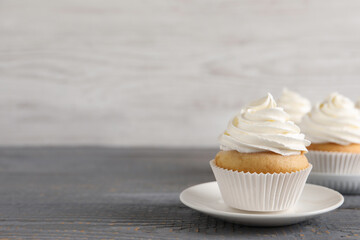 Delicious cupcake with cream on grey wooden table. Space for text