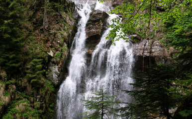 Naklejka premium Beautiful view of scenic waterfall with mossy rocks and green trees. Park of waterfalls Mendeliha in Sochi, Russia. Summer vacation in Caucasus mountains.