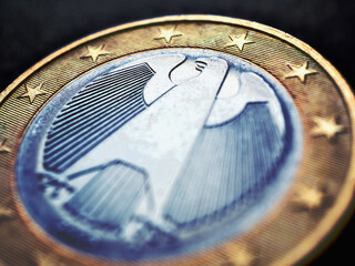 1 euro lies on a dark surface. The coin was issued in Germany. Obverse with the Federal Eagle. Close-up. Dramatic illustration for European Union currency and economy news. Increased contrast. Macro