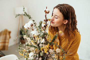 Blissful young woman smelling a flower arrangement at home