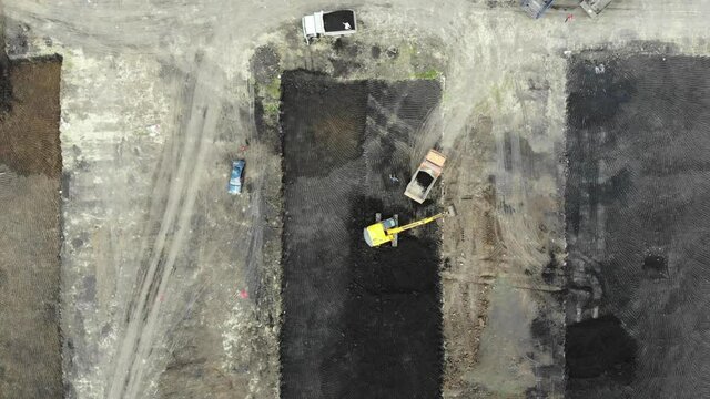 Aerial view of the construction site. Special machinery digs a pit. Work machinery. Machines digging pit. Construction process. Pit for building. Construction site from the air.