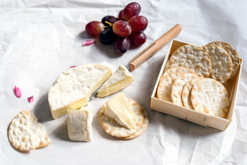 Camembert, grapes, and crackers on a white background.