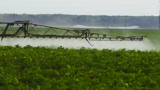 Tractor spraying glyphosate pesticides on farm field from above.Tractor with pesticide fungicide insecticide sprayer on farm land.