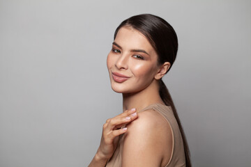 Cheerful young woman with natural manicured nails smiling on white background, studio portrait