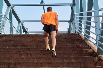 Sportsman jogging up the stairs in yellow running shoes.