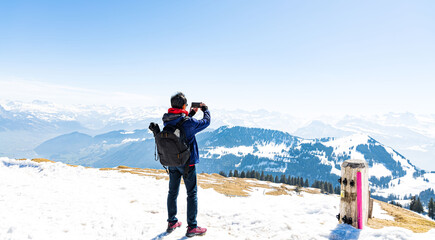 Happy time with young tourist blogger  taking photo by smartphone with snow mountain at Switzerland with blue sky background - obrazy, fototapety, plakaty