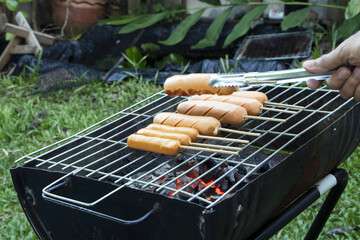 tasty hot dogs skewers cooking on grill. On a hot coal stove outside the house for a dinner party.