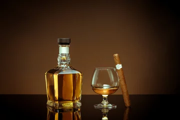 Rucksack close up view of cigar, bottle of cognac and a glass aside on color back.  © Dmitry Ersler
