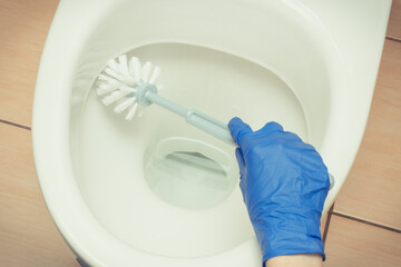Hand of cleaner using brush for cleaning toilet. Household duties concept
