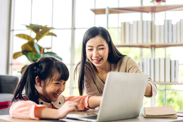 Mother and asian kid little girl learning and looking at laptop computer making homework studying...