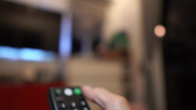 Man's hand presses the TV remote and turns off the smart TV A modern home with an emphasis on hands and remote controls.