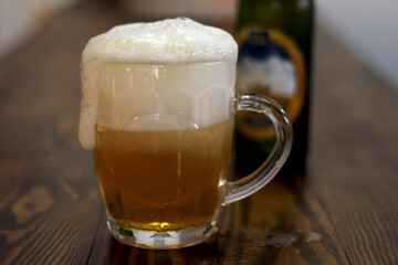 a glass of foamy fresh cold beer on the table