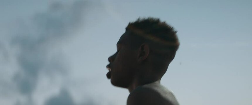 CU Portrait of Black African American teenager kid boy playing basketball alone on an outdoor court in the evening. High quality 4k footage