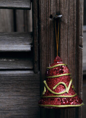 Christmas bell hanging from a wooden shutter with red and gold tones