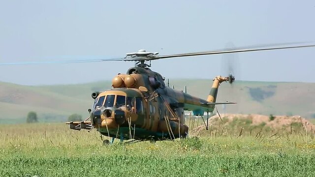 A military helicopter stands on the ground in a field with its propellers on. Armed conflict in Israel. Defense Army. Military aircraft on mission.