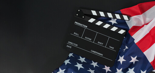 Black Clapper board or movie slate and Flag of the United States of America (USA.) on black background.