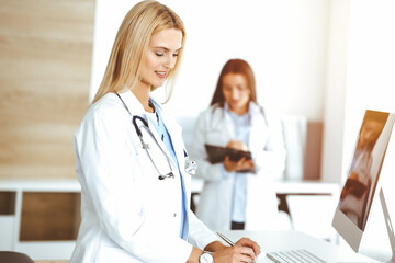 Doctor woman controls medication history records and exam results while using clipboard in sunny hospital . Medicine and healthcare concept