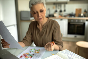 Focus on female hand holding yellow transparent capsules. Middle-aged woman reading instructions for medical use of medications. Medicine, health and healthy lifestyle concept