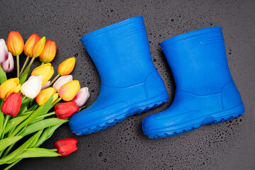 blue rubber boots with multicolored tulips on a black background.