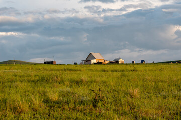 farm and residential wooden houses on a green meadow