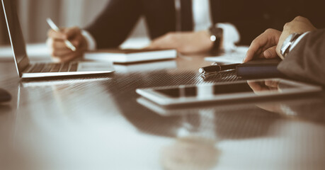 Unknown businessmen and woman sitting, using laptop computer and discussing questions at meeting in modern office, close-up
