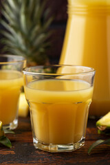 Freshly squeezed Pineapple juice in glass jug and two glasses on rustic wooden table