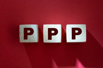 Word Public-Private Partnership PPP. Wooden small cubes with letters isolated on red background with copy space available. Business Concept image.