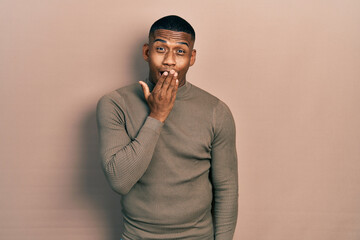 Young black man wearing casual turtleneck sweater bored yawning tired covering mouth with hand. restless and sleepiness.