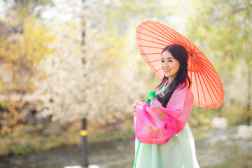 Korean girl wearing a hanbok wearing a red umbrella at Cheonggyecheon. Korea. Asian woman tourists.