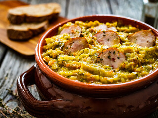 Cooked young cabbage with sausage on wooden table 
