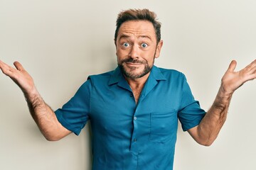 Middle age man wearing casual clothes clueless and confused with open arms, no idea and doubtful...