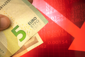 Euro money descending concept, euro banknotes in hand, currency going down background of red arrow,...