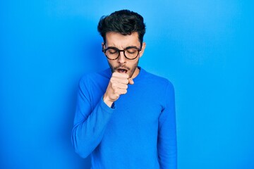 Young hispanic man wearing casual clothes and glasses feeling unwell and coughing as symptom for cold or bronchitis. health care concept.