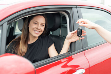 An attractive woman in a car gets the car keys. Rent or purchase of auto - concept.