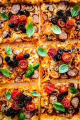 Fototapeta na wymiar Pizza with white mushrooms, sausage, tomatoes, black olives, parmesan and mozzarella on wooden background 