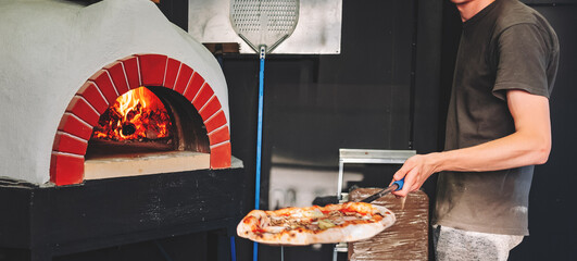 chef takes pizza. Italian pizza is cooked in a wood-fired oven