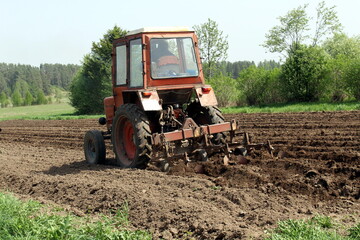 Obraz premium Red tractor making paths for planting potatoes