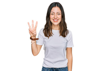 Obraz na płótnie Canvas Young beautiful woman wearing casual white t shirt showing and pointing up with fingers number three while smiling confident and happy.