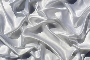 Satin white fabric with sharp shadows folds on the surface in the form of a drapery