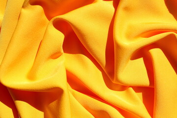 The texture of the yellow fabric lies in the form of a drapery