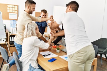 Group of business workers smiling happy celebrating making tower with fists together at the office.