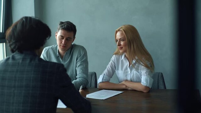 Rear view of professional young woman and man headhunters holding interview with male job seeker. Caucasian HR managers having job interview with young guy in suit. Tracking shot in slow motion.