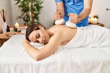 Obraz na płótnie Canvas Young woman reciving herbal pouches thai massage at beauty center.